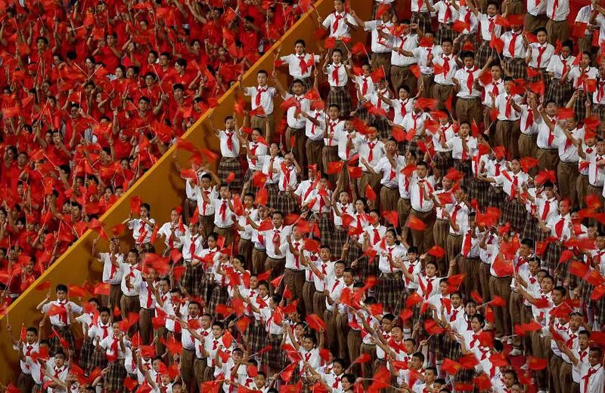 观众观看文艺演出《伟大征程》时，挥舞手中的旗帜。（法新社）