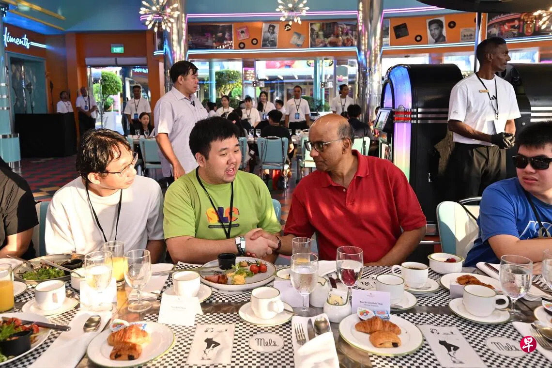 尚达曼总统（前排右二）于星期六在新加坡环球影城与29岁中等自闭症患者姚启扬（前排左二）及其他受益者交流。 （主办方提供）