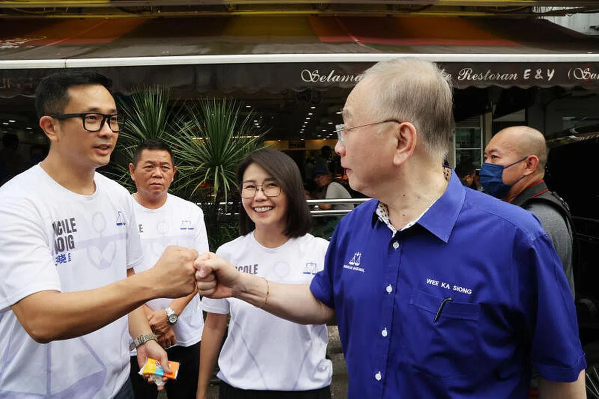 马华总会长魏家祥（右）星期一（11月14日）南下新山为马华地不佬国会议席候选人王晓庭（中）站台，与“妇唱夫随“协助竞选的郭光荣（左）碰拳致意。（邝启聪摄）