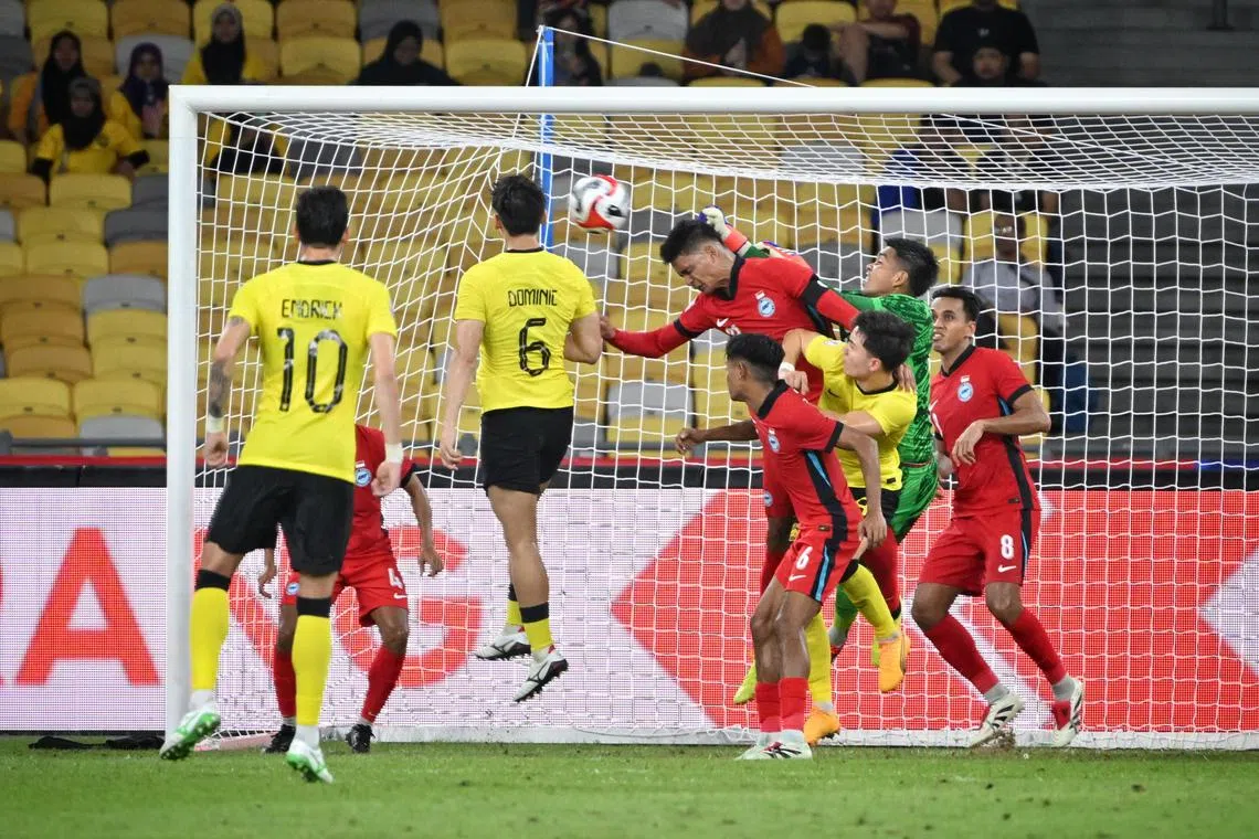 雄狮大将萨夫万（顶球者）头球解围化解危机。在他带领下，我国成功守和马来西亚。（海峡时报）