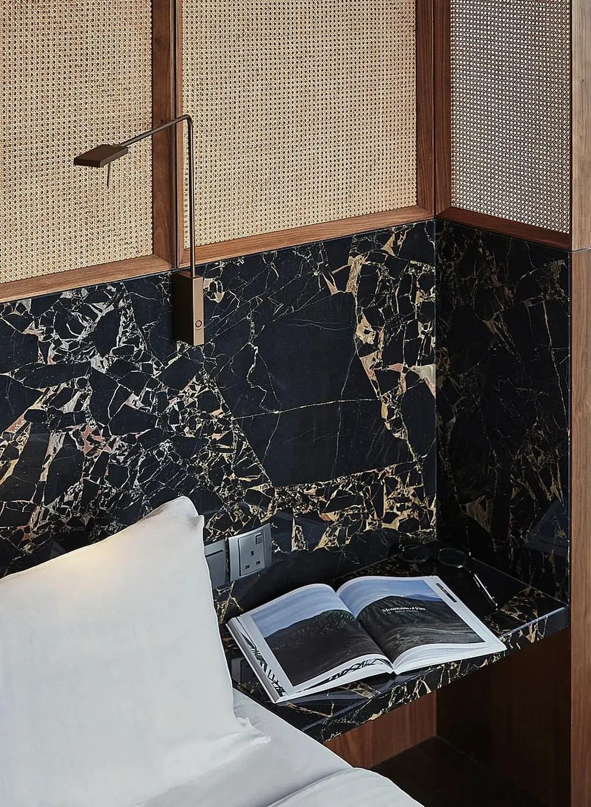 主卧室床头墙面的藤编设计，搭配黑金色纹路的大理石，打造高雅氛围。（Atelier Here提供图片）