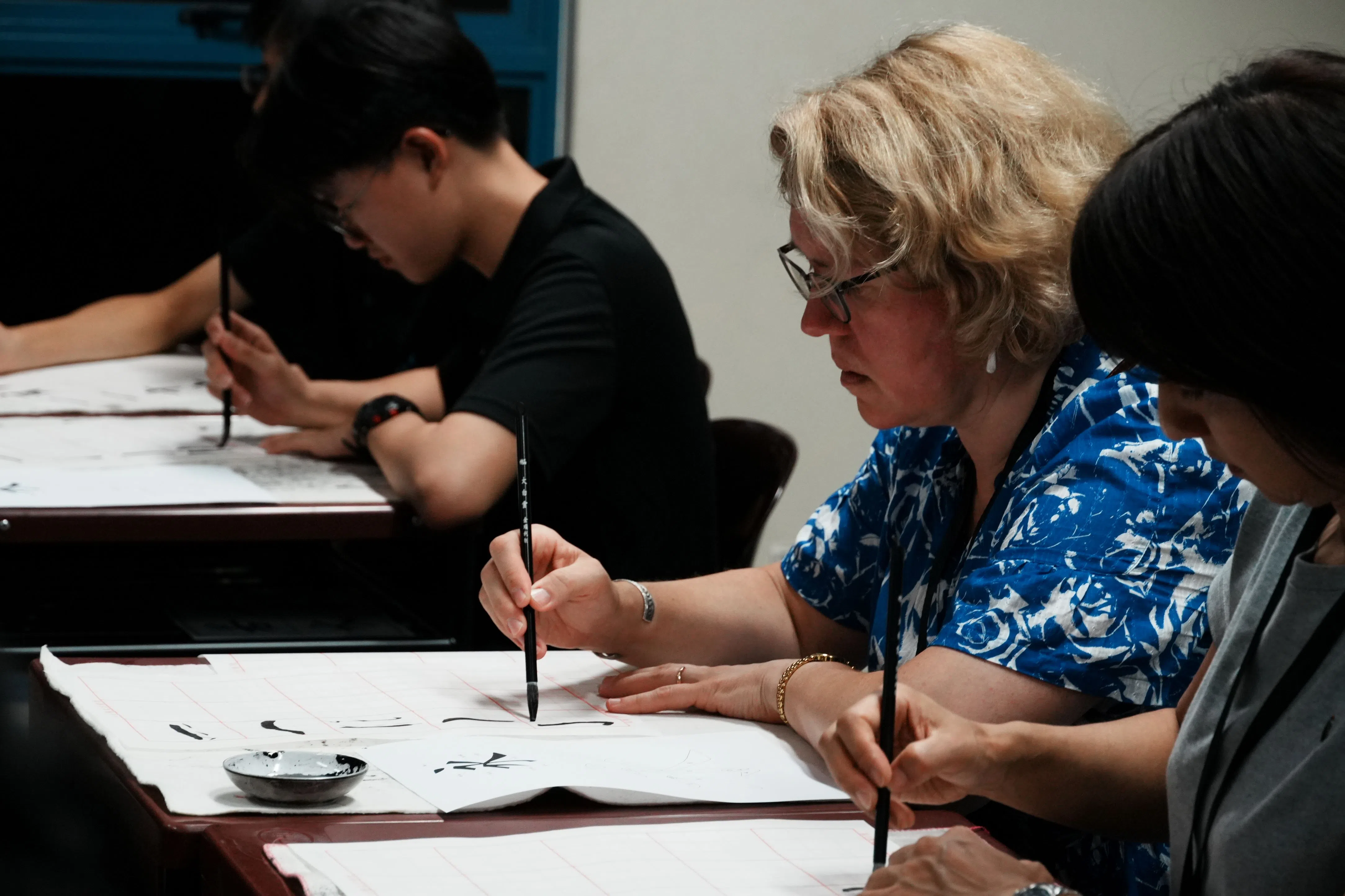 在华中书法学会学生的指导下，连带队老师也能对书法艺术有沉浸式体验。（亚太青年领袖峰会多媒体组提供）