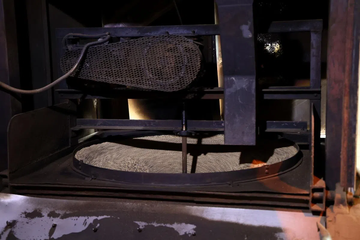 【炒麻】芝麻放入大型生铁锅，由机械翻炒。一些麻油厂已改用封闭式机器，但胡元兴坚持传统用铁锅翻炒。（龙国雄摄）