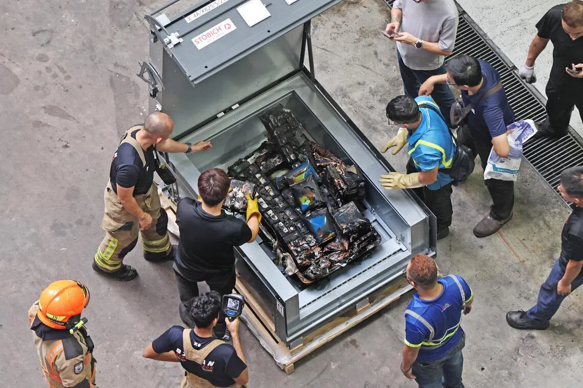 消防员在确保电池冷却后，将失火电池装进一个特制的防火箱中运走。（陈渊庄摄）