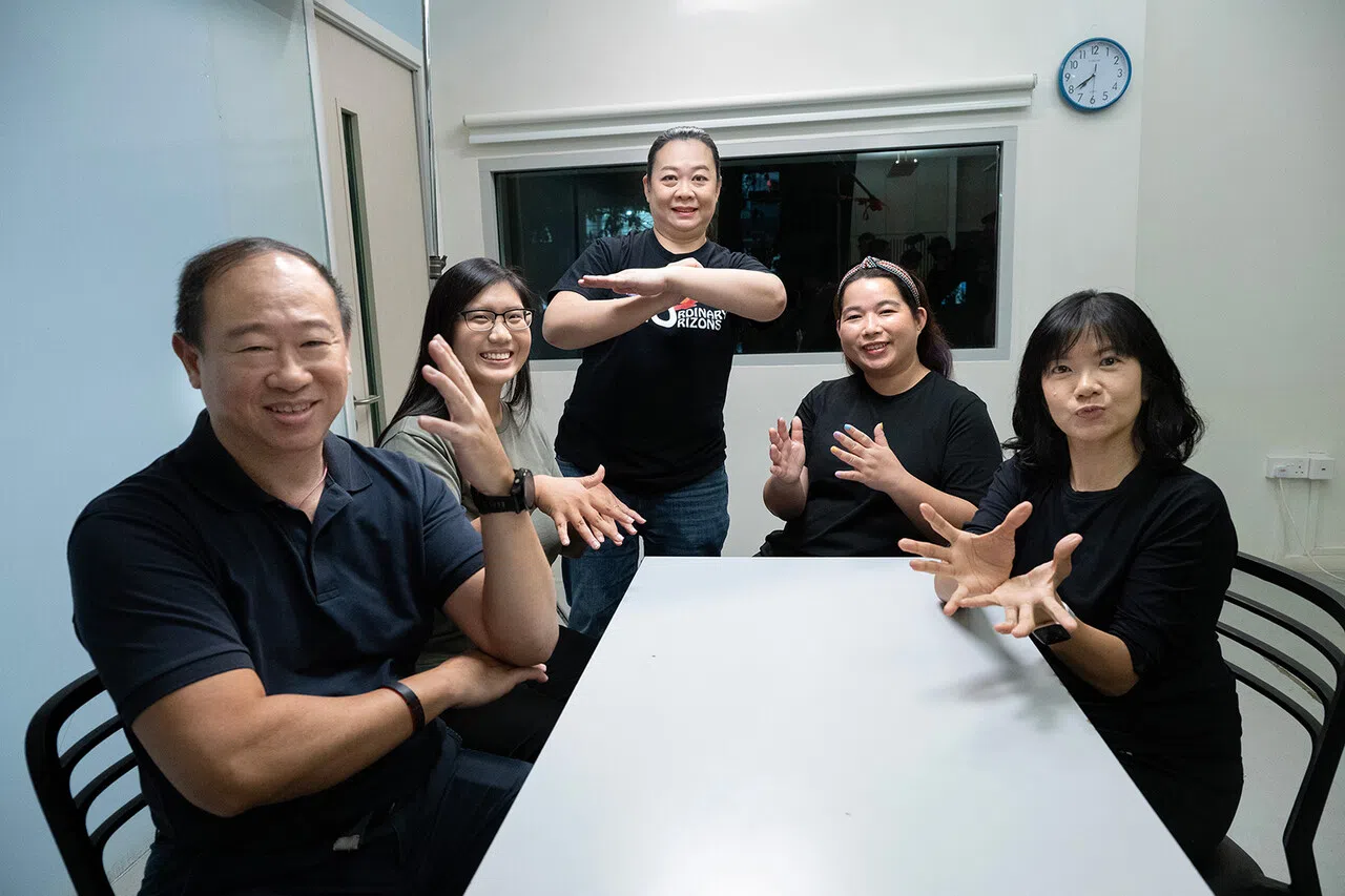 吴丽丽（中）与学员示范“树”“花”“日出”等自然主题的手语词汇。（档案照）