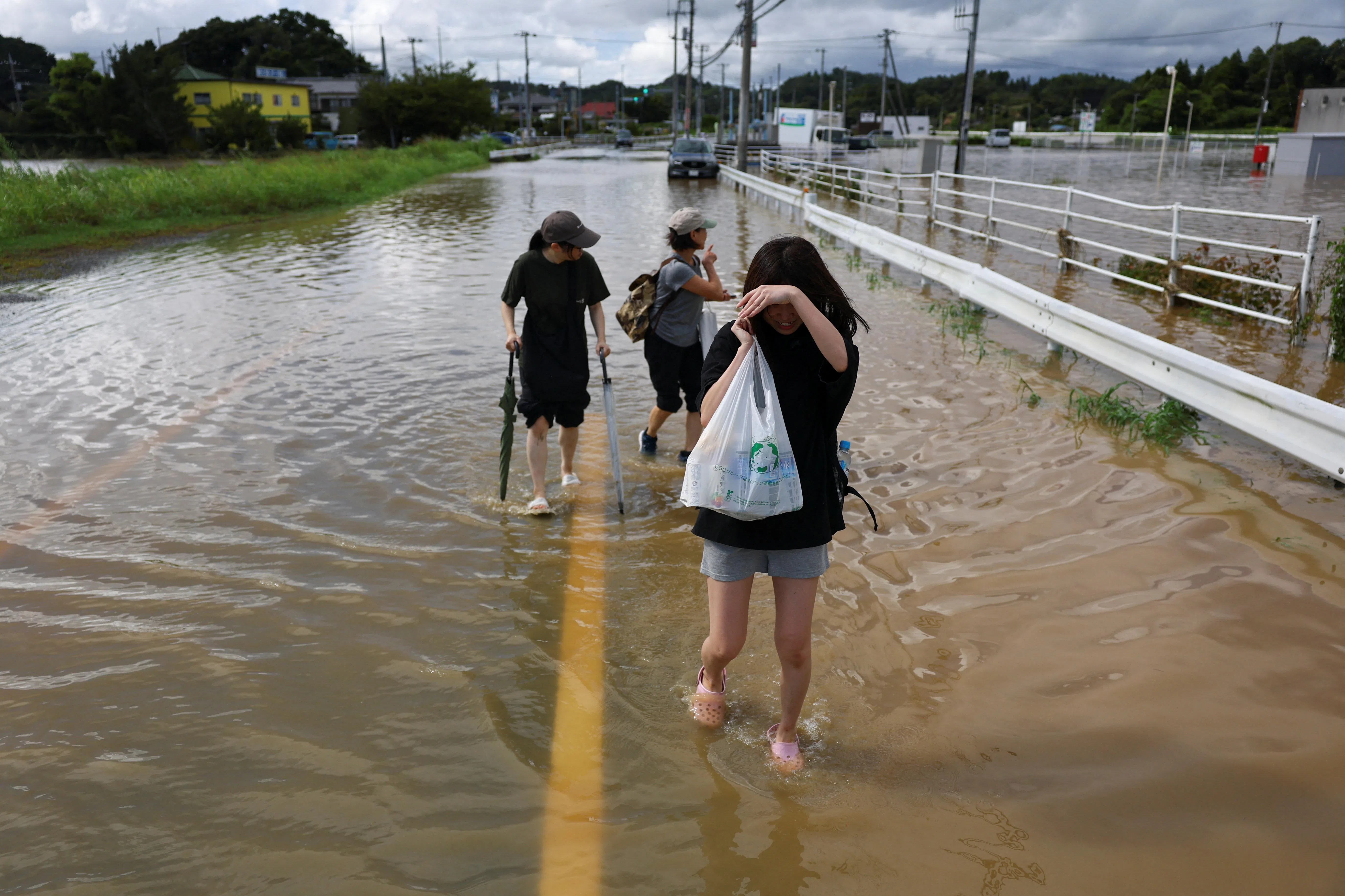 大网白里市强降雨过后，多处洪水星期五（8月14日）仍未消退，当地居民外出时得涉水行走。（路透社）