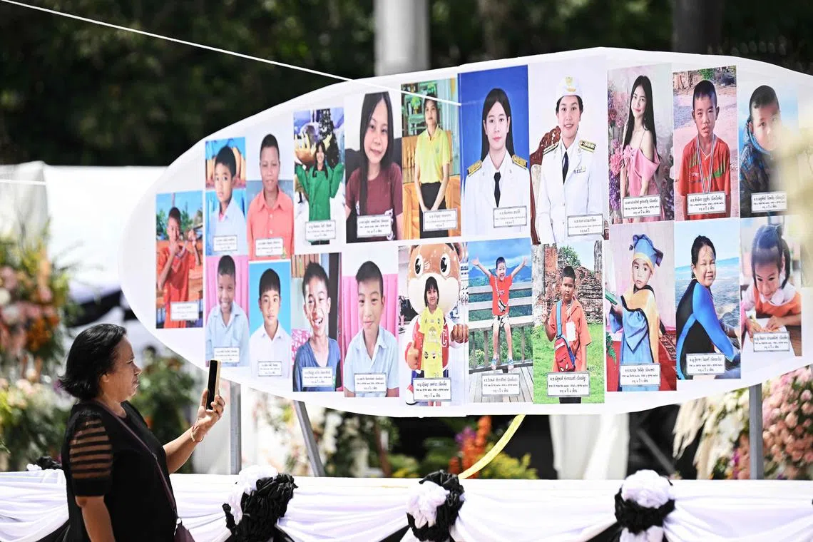 送殡仪式上挂上23名死者的照片，让人看了不禁鼻酸。（法新社）