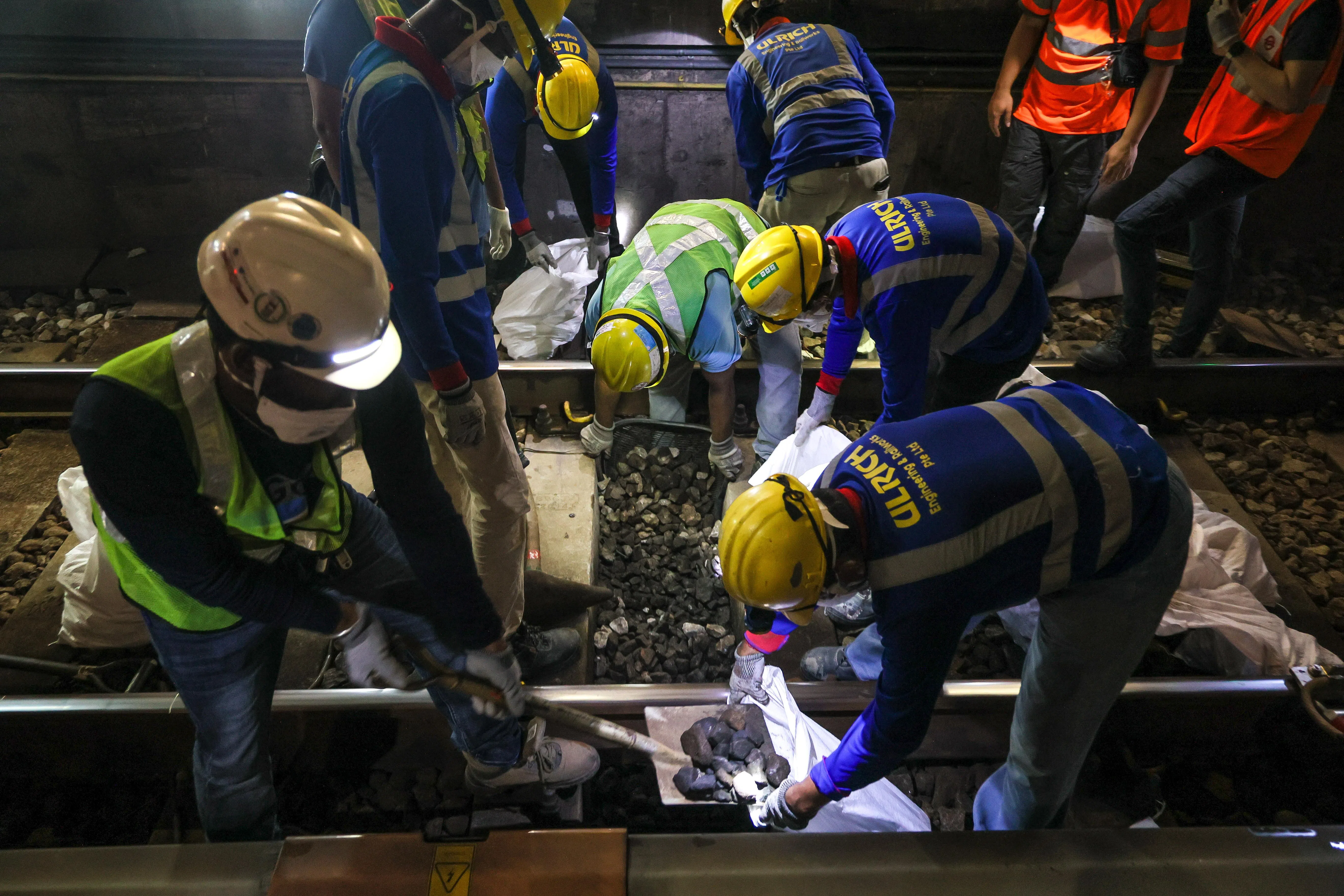 在确定需要更换的区段后，工作人员会先在轨枕间用手挖出退化的碎石；在极有限的夜间工程时段，只能靠传统的手动作业，因为搬运机械进出轨道需要更长时间。（张俊杰摄）