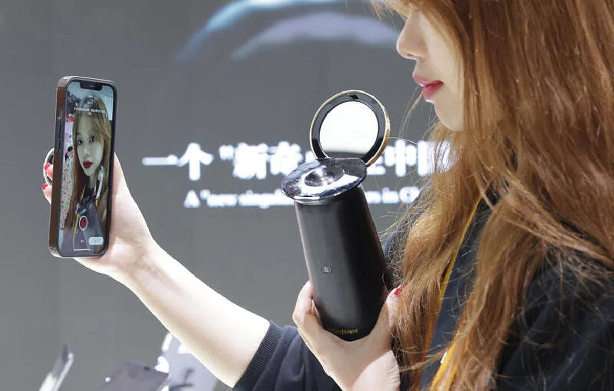 观众通过手机APP试用圣罗兰美妆展台上的“口红打印机”。（中新社）