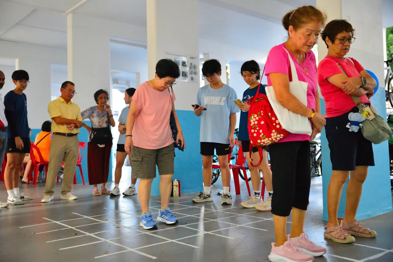 马林百列—布莱德岭集选区议员、国会议长谢健平（黄衣站立者）与学生领袖和居民一同观看正在进行的游戏。（南洋初级学院提供）