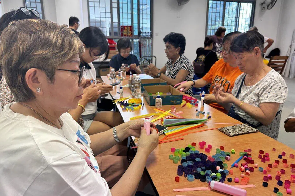 女皇镇的嘉年华倒数活动，号召2025名居民和义工，共同完成一幅边2米长的方形卷纸艺术作品，迎接2025年。作品将在倒数活动后，于女皇镇民众俱乐部展示。图为30多名来自丹戎巴葛集选区和拉丁马士区的居民和义工，参与卷纸手工活动。（女皇镇选区办事处提供）