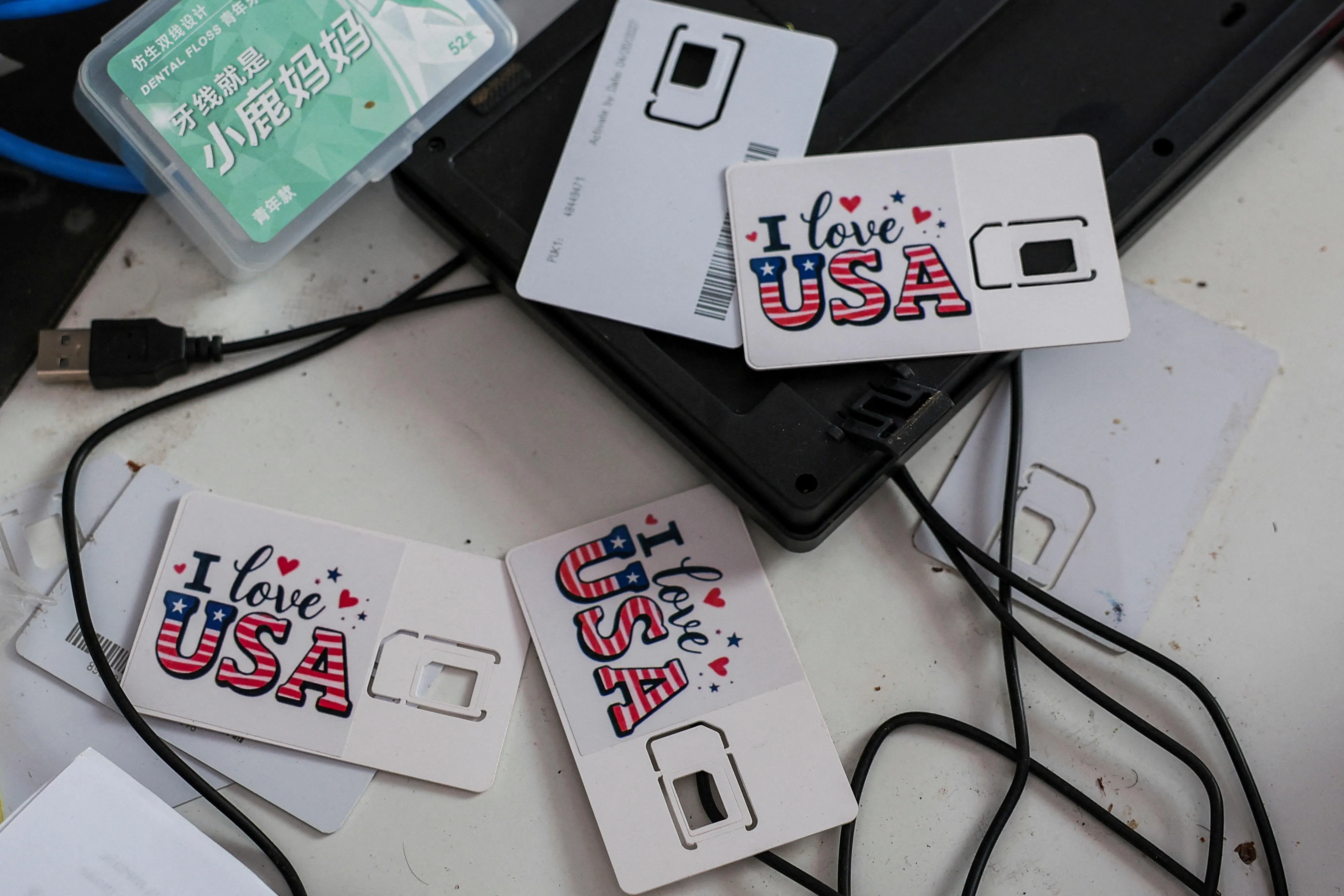 这个诈骗园区的E区曾被用作跨境电诈的枢纽，办公场桌上还放着印有“我爱美国”字样的SIM卡。（路透社）