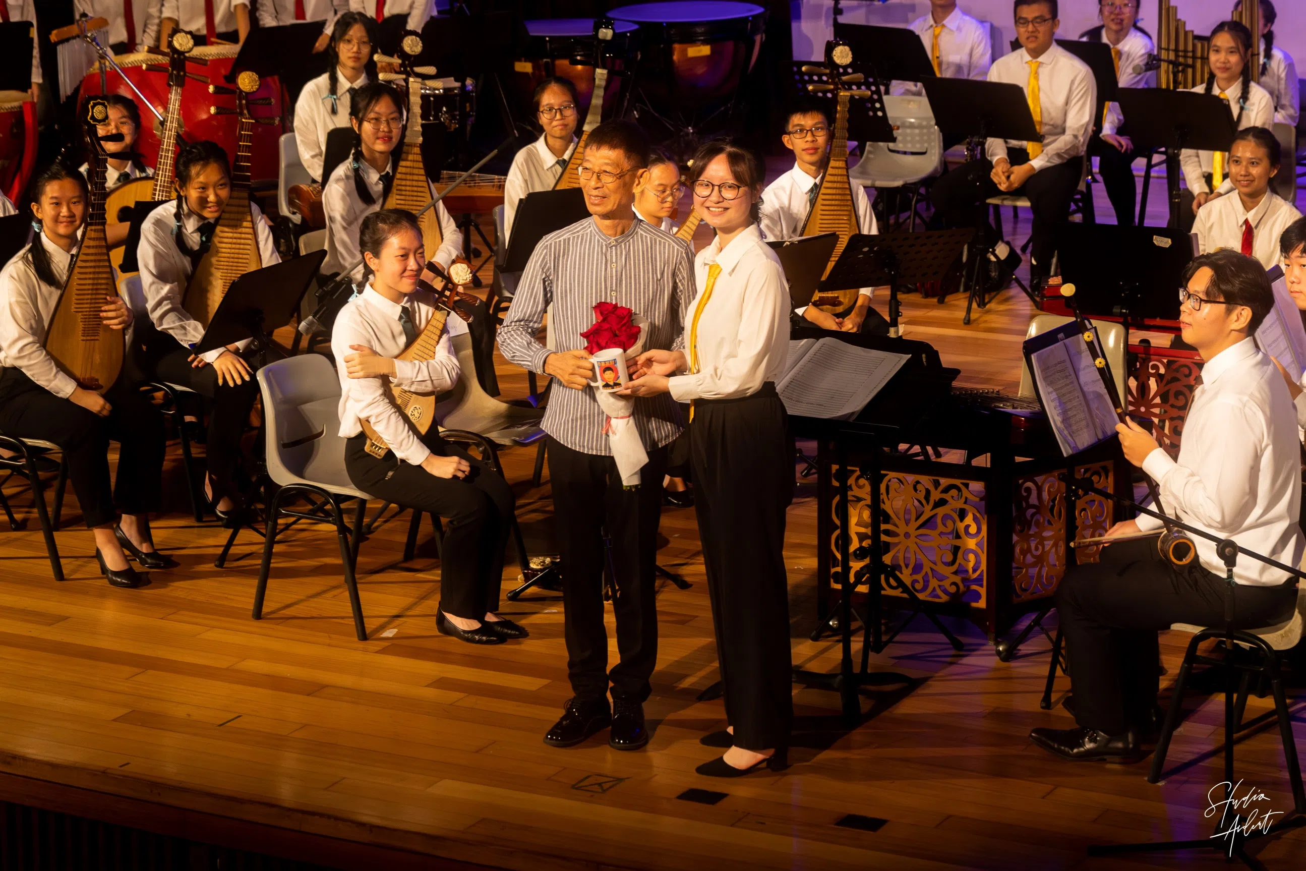 学生指挥李嘉仪（前排右）为乐团指挥魏砚铭教授（前排左）献上纪念品。（华中摄影学会提供）