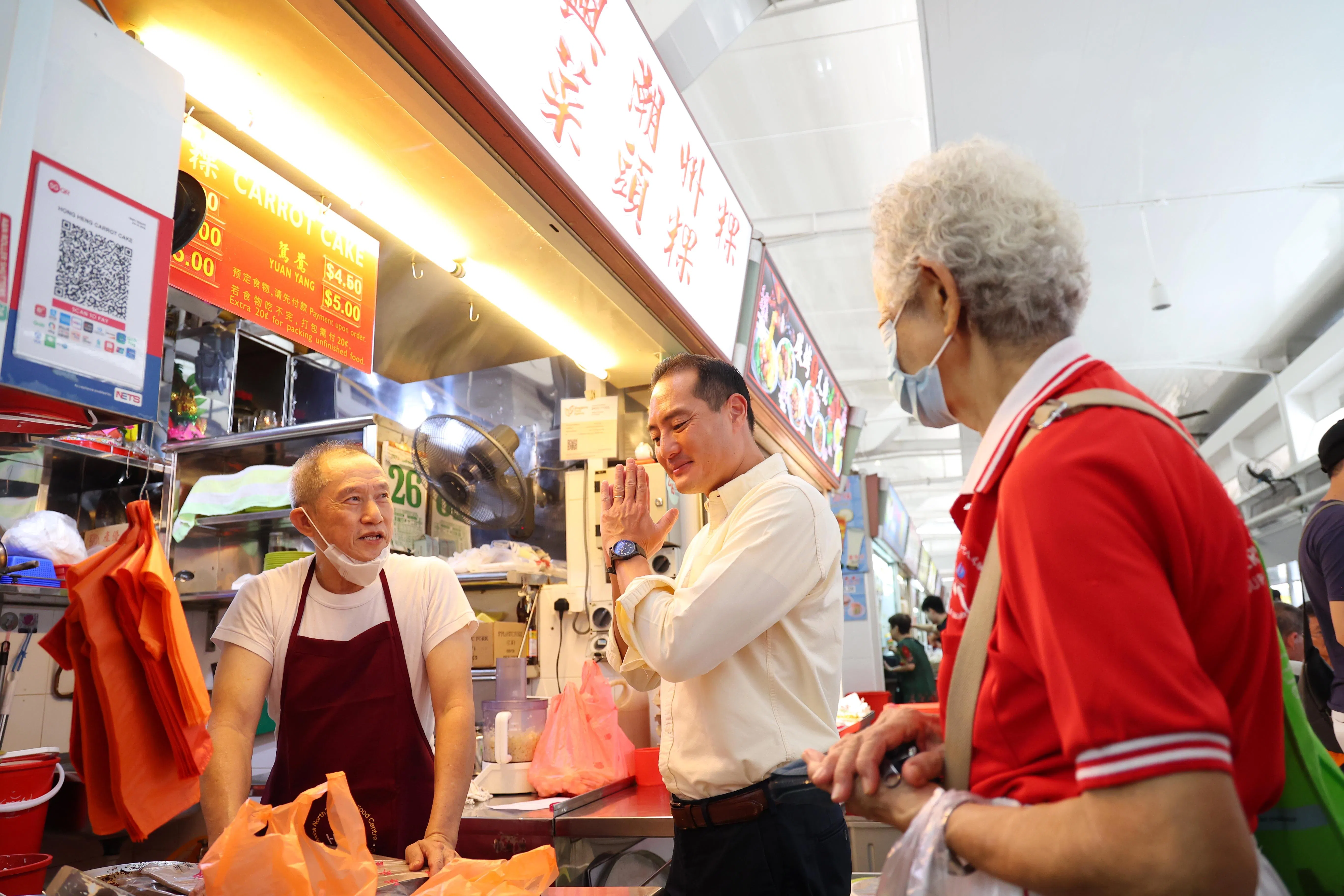 勿洛北1街第216座巴刹与熟食中心商联会主席许林宝（左）与通讯及新闻部兼国家发展部高级政务部长陈杰豪（中）互动。（林明顺摄）