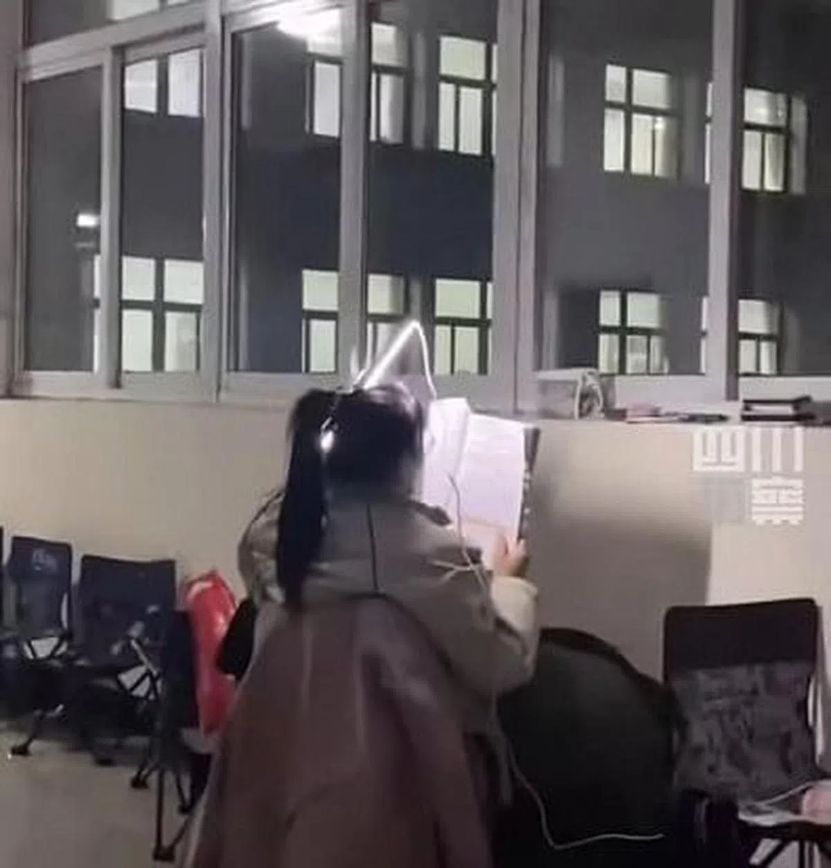 女生将灯管插入头发中照明读书。（互联网）