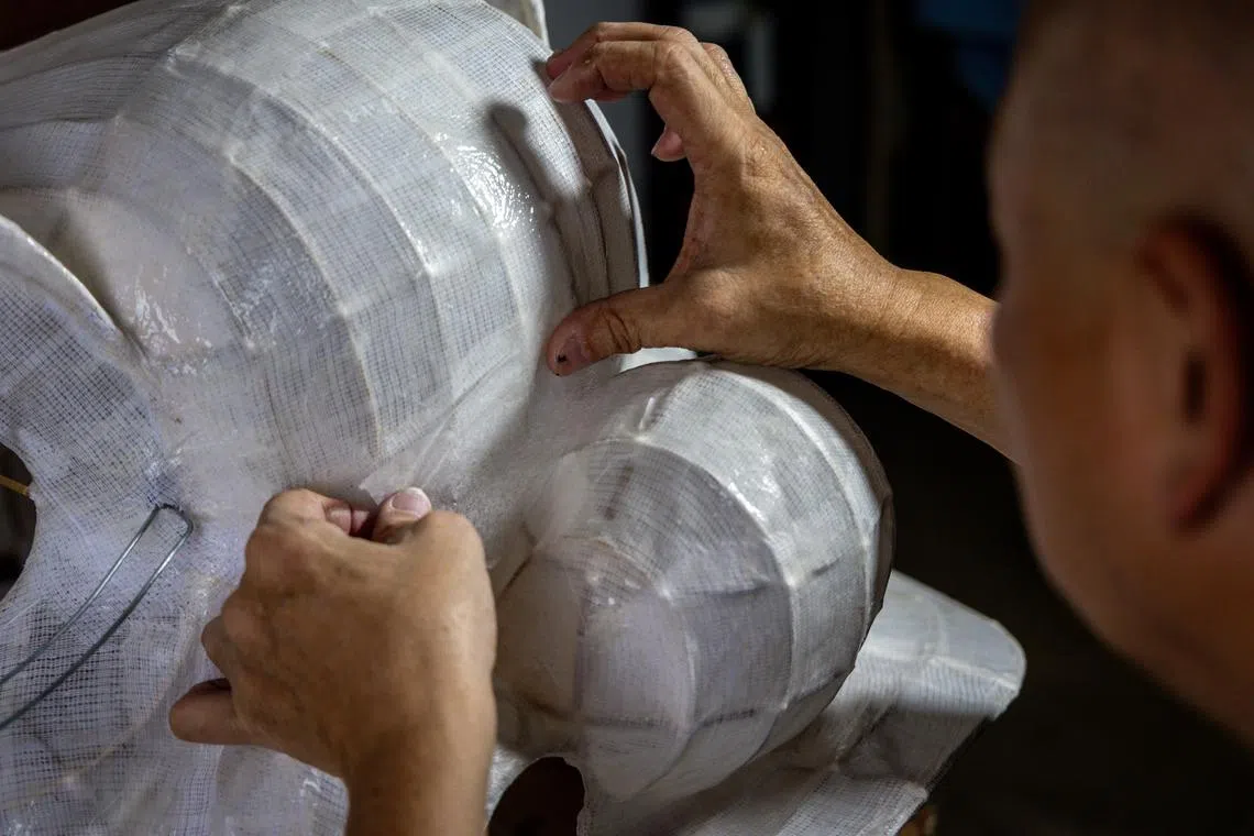 在狮头骨架上贴上涂有浆糊的纱布进行塑形，这个步骤称为扑。（叶振忠摄）