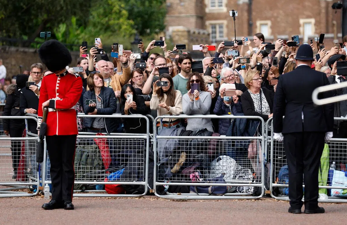 女王灵柩队伍经过时，民众纷纷举起手机相机，记录历史性的一刻。（路透社）