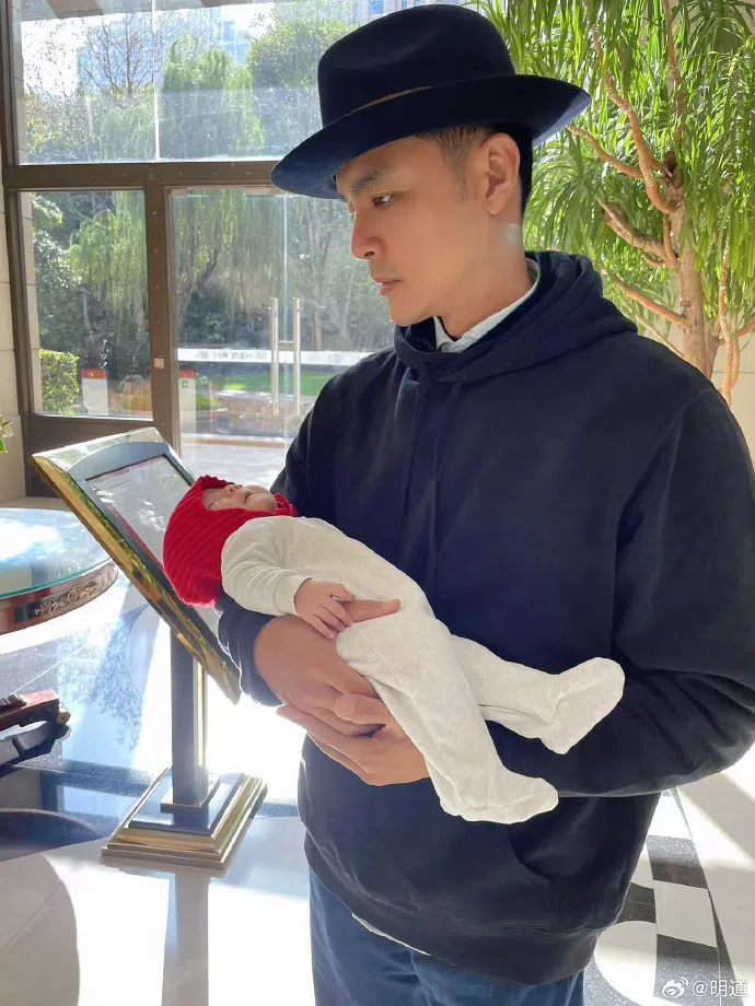 明道以帽子配长袖寒衣造型，捧着爱女拍照。（取自明道微博）