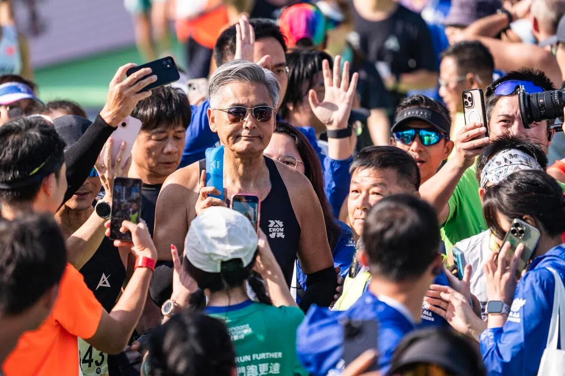 70岁的香港影星周润发（银发戴眼镜者）连续第四年参赛，并顺利完成10公里跑赛事，在冲线后受到众人欢迎。（中新社）