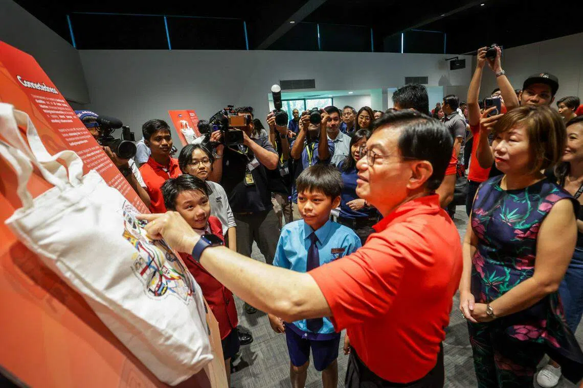 副总理兼经济政策统筹部长王瑞杰（右二）在活动现场与参与设计礼包的残障创作者交流，图为他和两名小小艺术家讨论创作灵感。（叶振忠摄）
