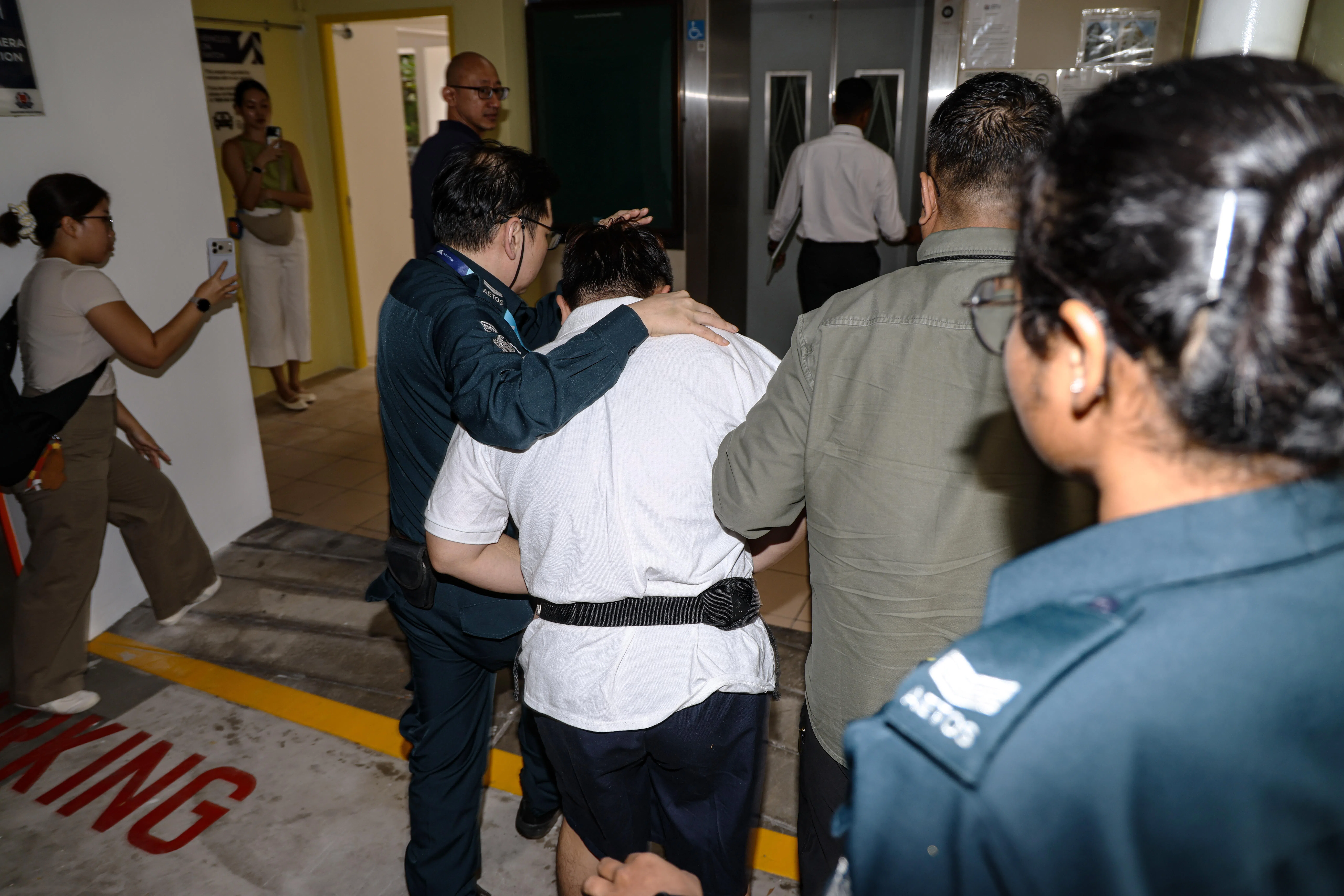 傅威利全程低头回避媒体镜头，在接受调查人员问话时仅低声回应。（关俊威摄）