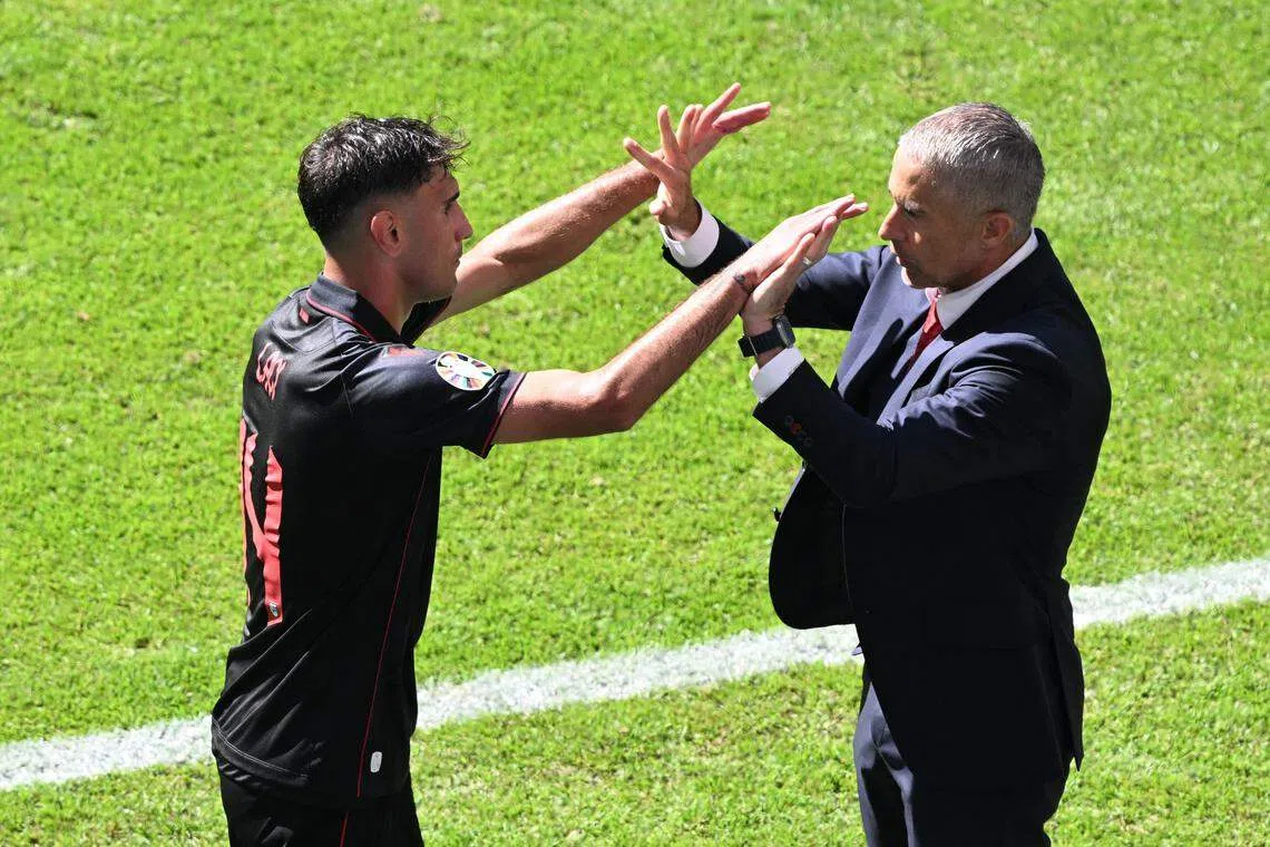 阿尔巴尼亚主帅西尔维尼奥（右）上一轮与被换下的球队进球功臣拉齐击掌。（路透社）