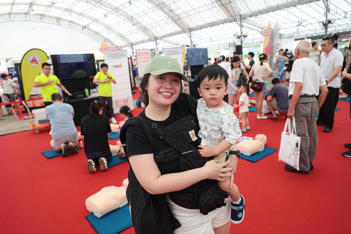 王思桦抱着一岁大的儿子，参加三巴旺首个社区应变能力日现场的心肺复苏法演示。（李冠卫摄）