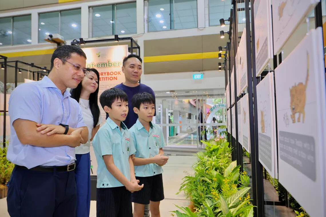 教育部长李智陞（右一）星期六到文礼社区俱乐部出席“猫咪月庆”嘉年华，欣赏童书绘本创作赛季军得主、10岁双胞胎哥哥沈晋祥（左一）和弟弟沈晋安的作品。两兄弟的父亲沈华山（后排右起）和母亲何晓翠也来支持。（龙国雄摄）