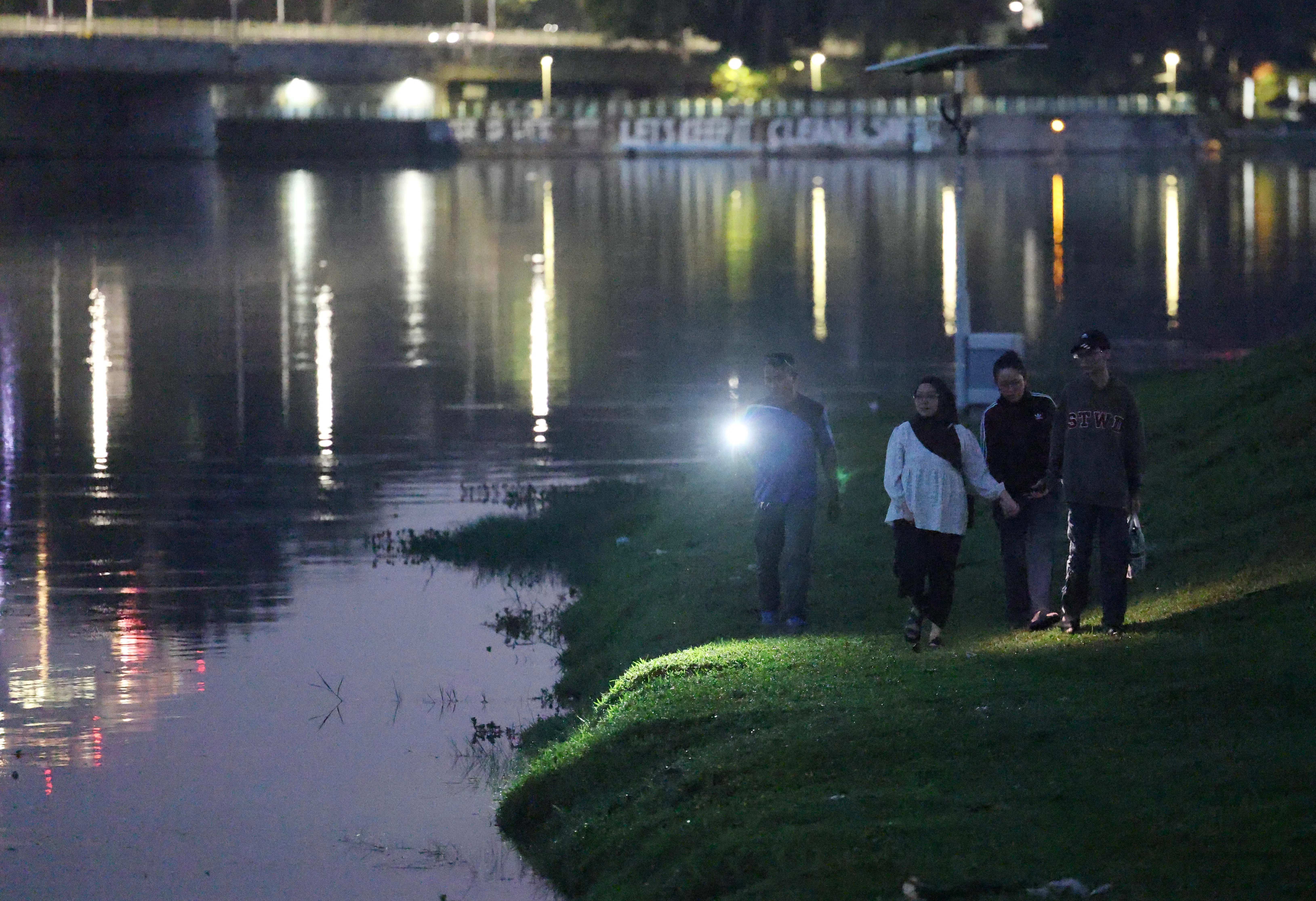 家属2月26日天未亮就返回案发现场，拿着手电筒沿着河岸寻找失踪的丹尼尔。（郑一鸣摄）