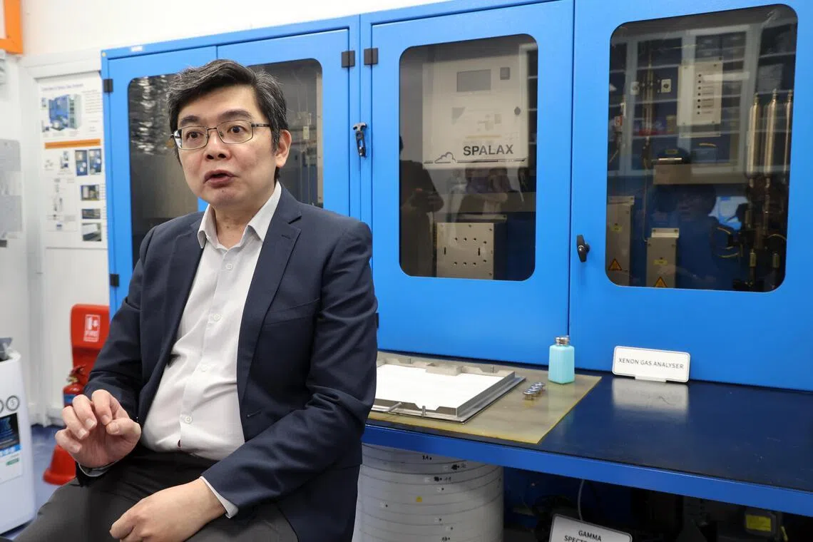 环境局辐射保护与核科司司长洪国杰说，人工智能等新兴领域有更大的吸引力，要招人才投身核安全领域有挑战，但仍有人愿意加入，团队也正在扩大。图后方是放射性核素氙（xian念第一声，xenon）监测系统。（邝启聪摄）