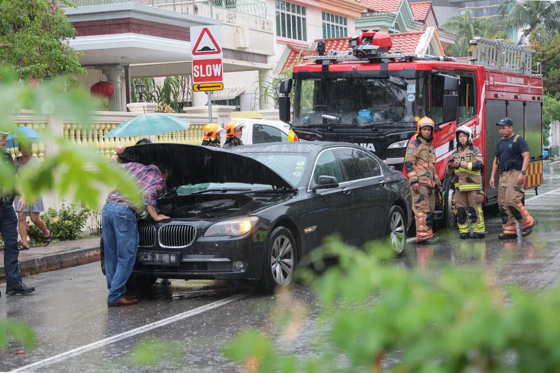 一辆宝马轿车在雨中于运涛道上抛锚，民防人员也到场支援。（李冠卫摄）
