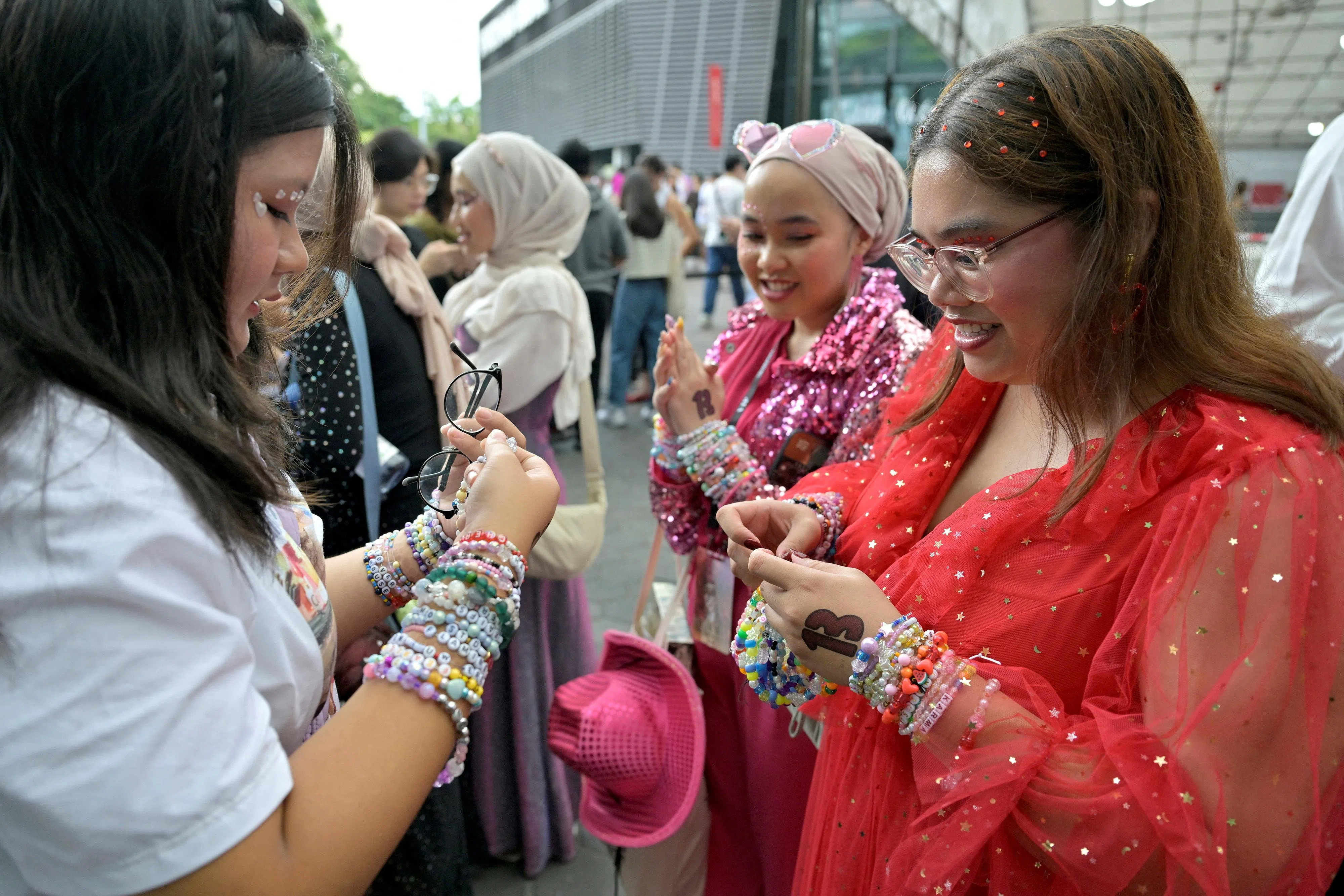 泰勒丝的粉丝在体育场外交换友谊手链。（路透社）