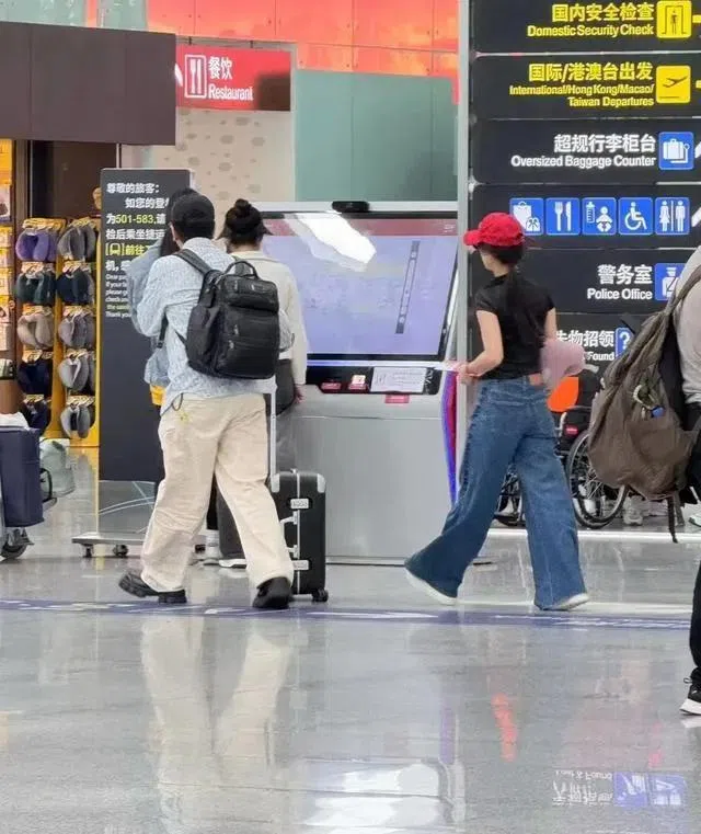 网民爆料称在广州机场见到杨子（背背包者）和黄圣依（戴红帽者），指他们飞往新加坡。（互联网）