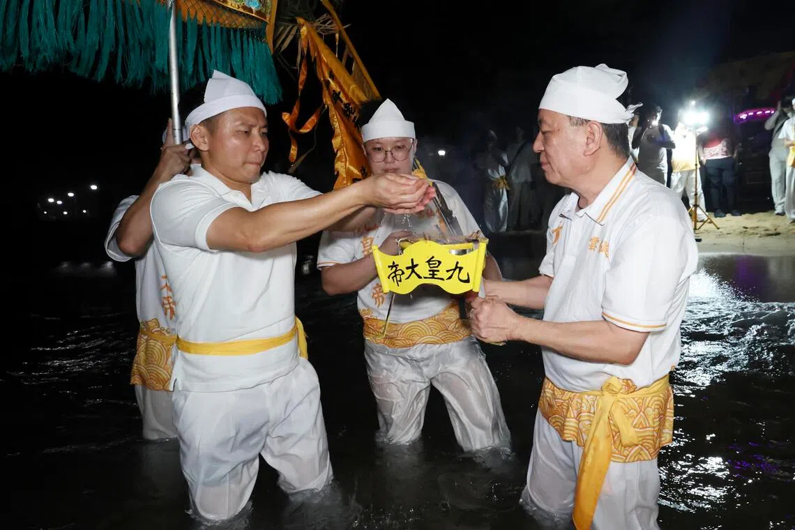 内政部兼社会及家庭发展部高级政务部长吴培铭（左）正下海请水，恭请九皇大帝圣驾回宫安座。（郑一鸣摄）