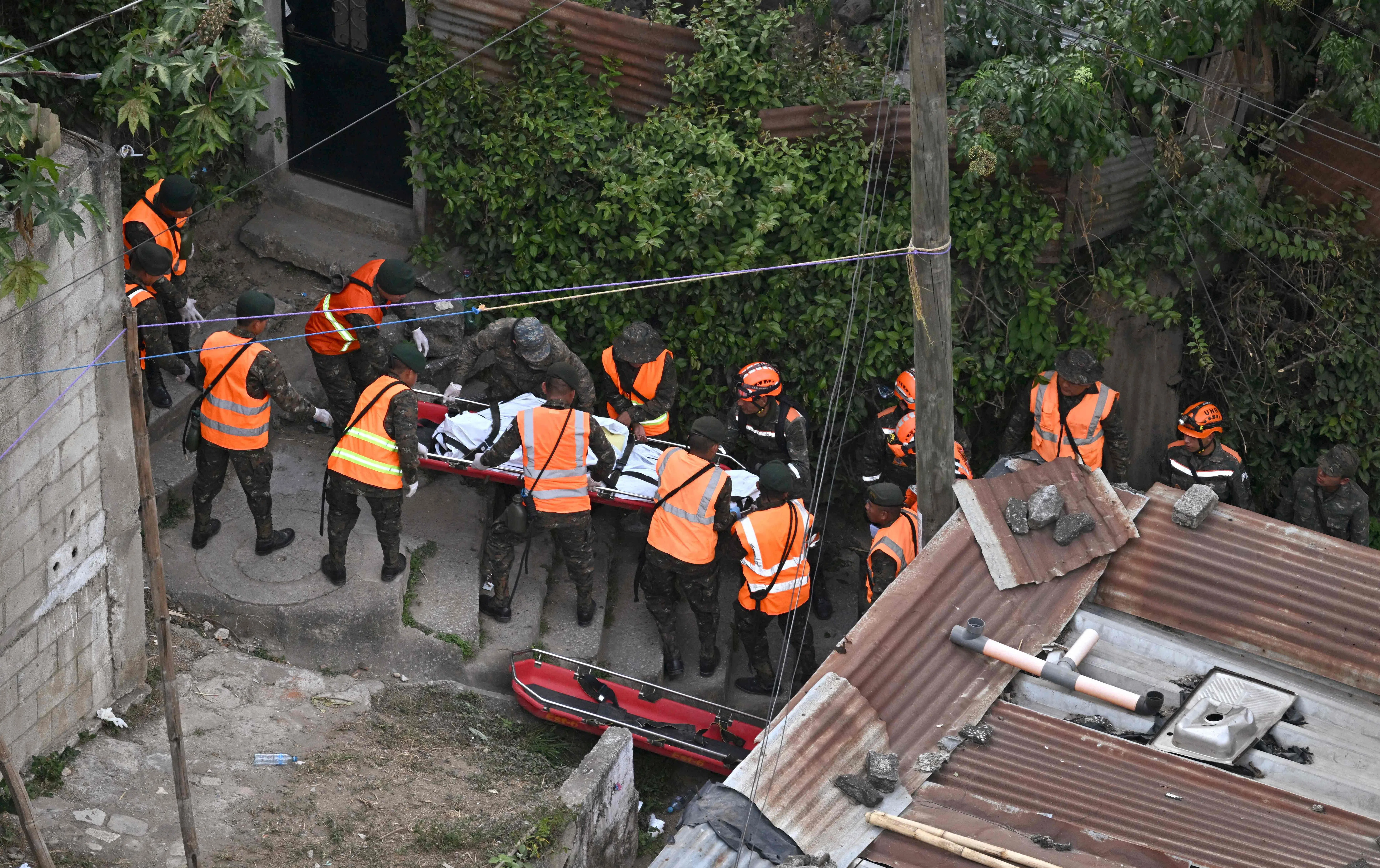 军人与警察排成一排，把从浑浊的水中拉出的遗体，以担架抬上斜坡。（法新社）