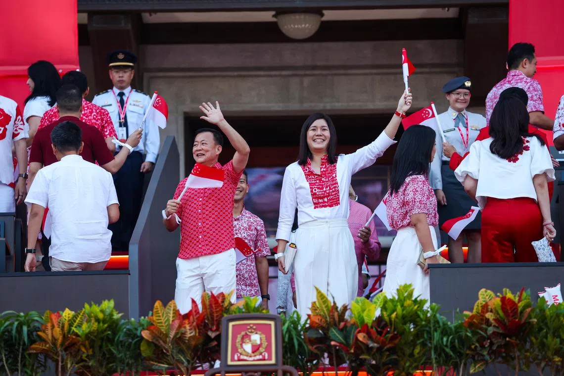 李蕙莹（右）与宏茂桥集选区议员赖添发（左）等后座议员和非选区议员一起入场。她的庆典服饰是与创作“乐乐体”书法的自闭少年李俊乐，以及本地裁缝工作室一起合作设计的，印有四种官方语言的“前进吧，新加坡”。（林明顺摄）