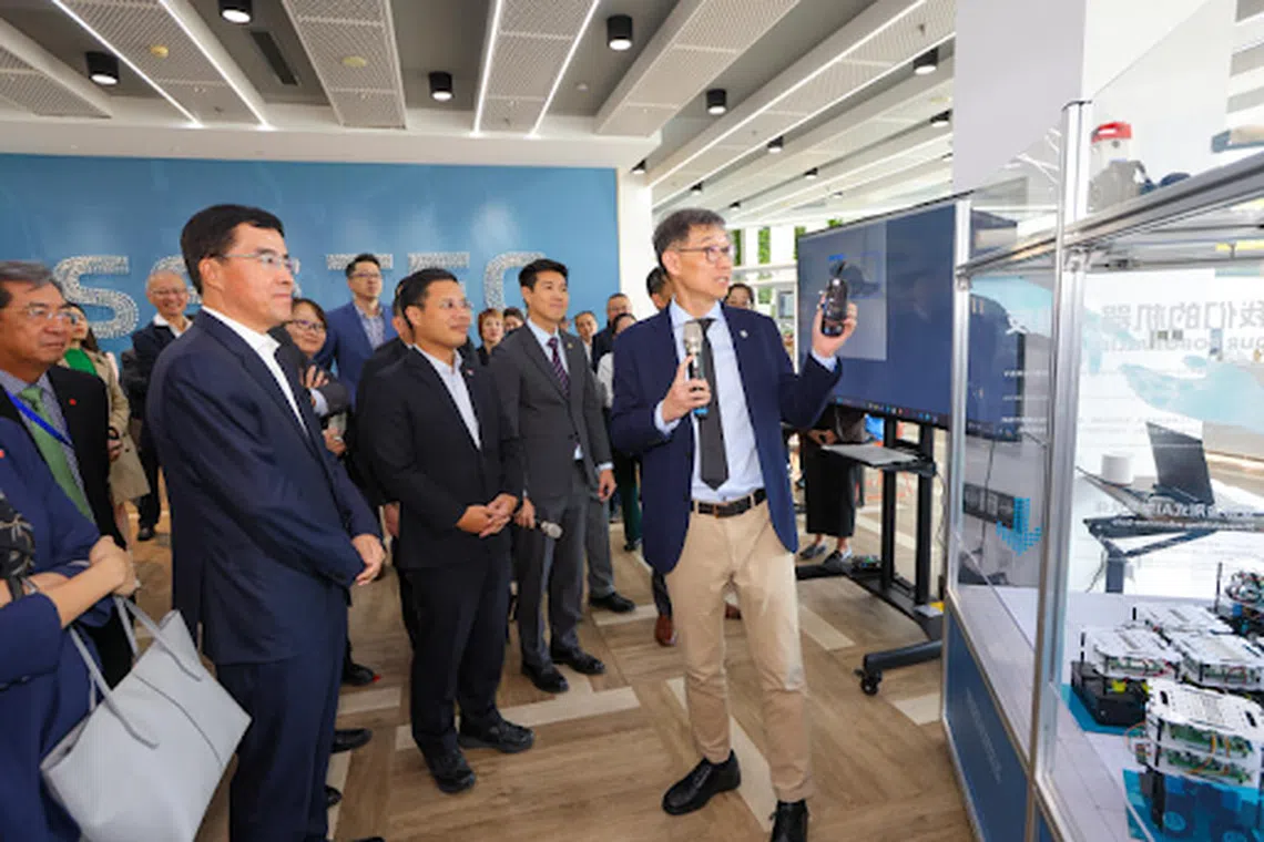 新科大校长方国光教授（右一）星期四（9月26日）在设于天津生态城的新加坡科技大学研究与创新中心，向国家发展部长李智陞（中）示范如何使用机器人定期检查假天花板是否有老鼠乱窜。左一为滨海新区区委书记连茂君。（国家发展部提供）