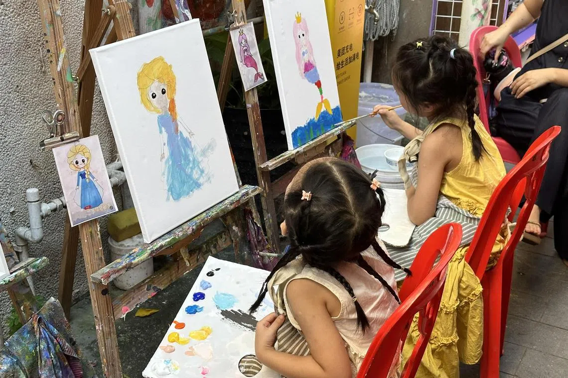 深圳大芬油画村大街小巷摆满画架和椅子，吸引到访游客尝试油画体验。（林煇智摄）