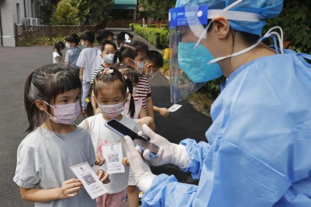 9月1日，在上海新世纪虹桥幼儿园，医护人员正在为幼儿进行核酸检测前的扫码登记。（中新社）