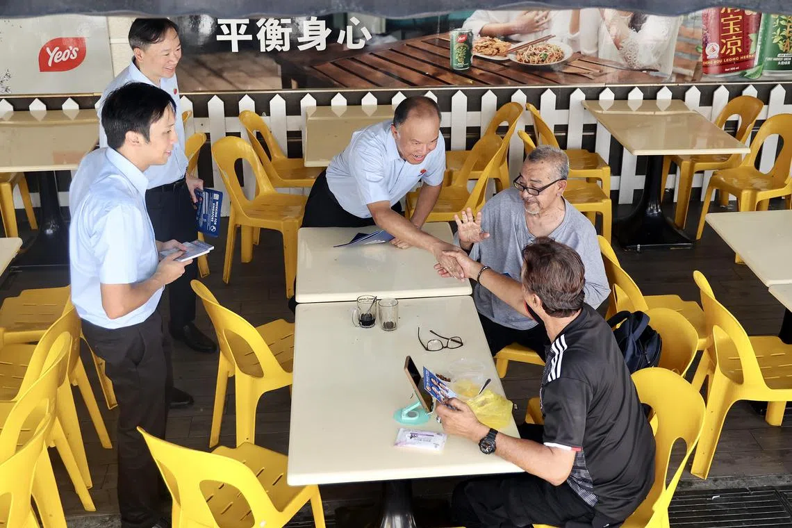 淡滨尼集选区候选人唐光伟（左起）、王锐斌博士和费沙走访淡滨尼21街市镇中心，向选民分发竞选传单。（陈斌勤摄）