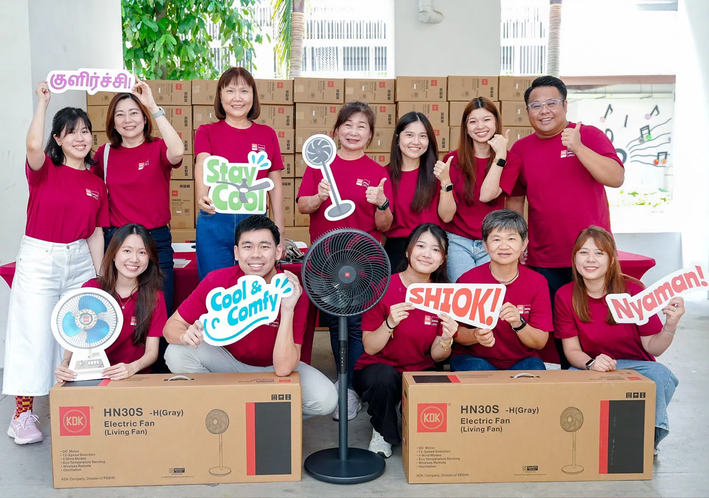 Capital Distributors staff with 100 KDK stand fans prepared for distribution to residents.