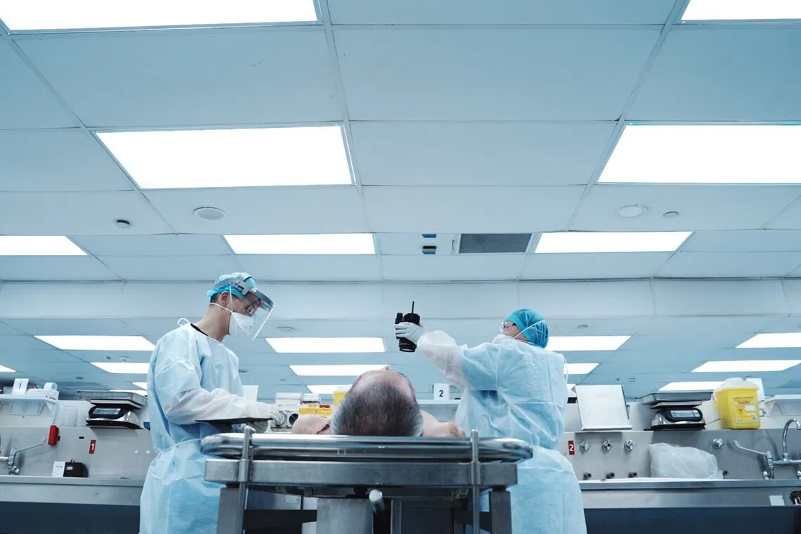 法医和助理详细地检验遗体，确保不错过任何线索。（搬演画面）（新传媒提供）