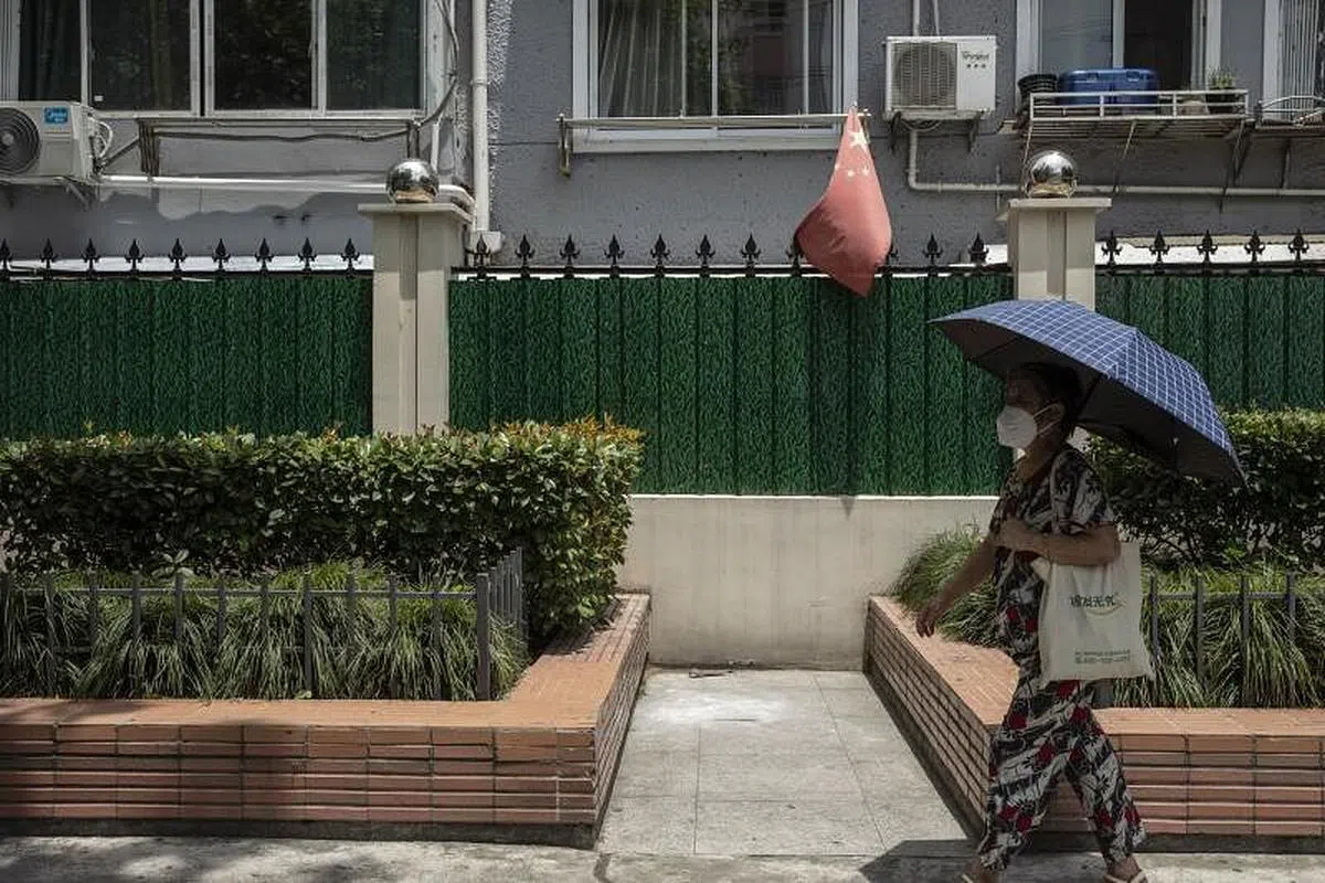 上海一名撑着伞的路人，周三（7月6日）经过一个因疫情而围封的小区。（彭博社）