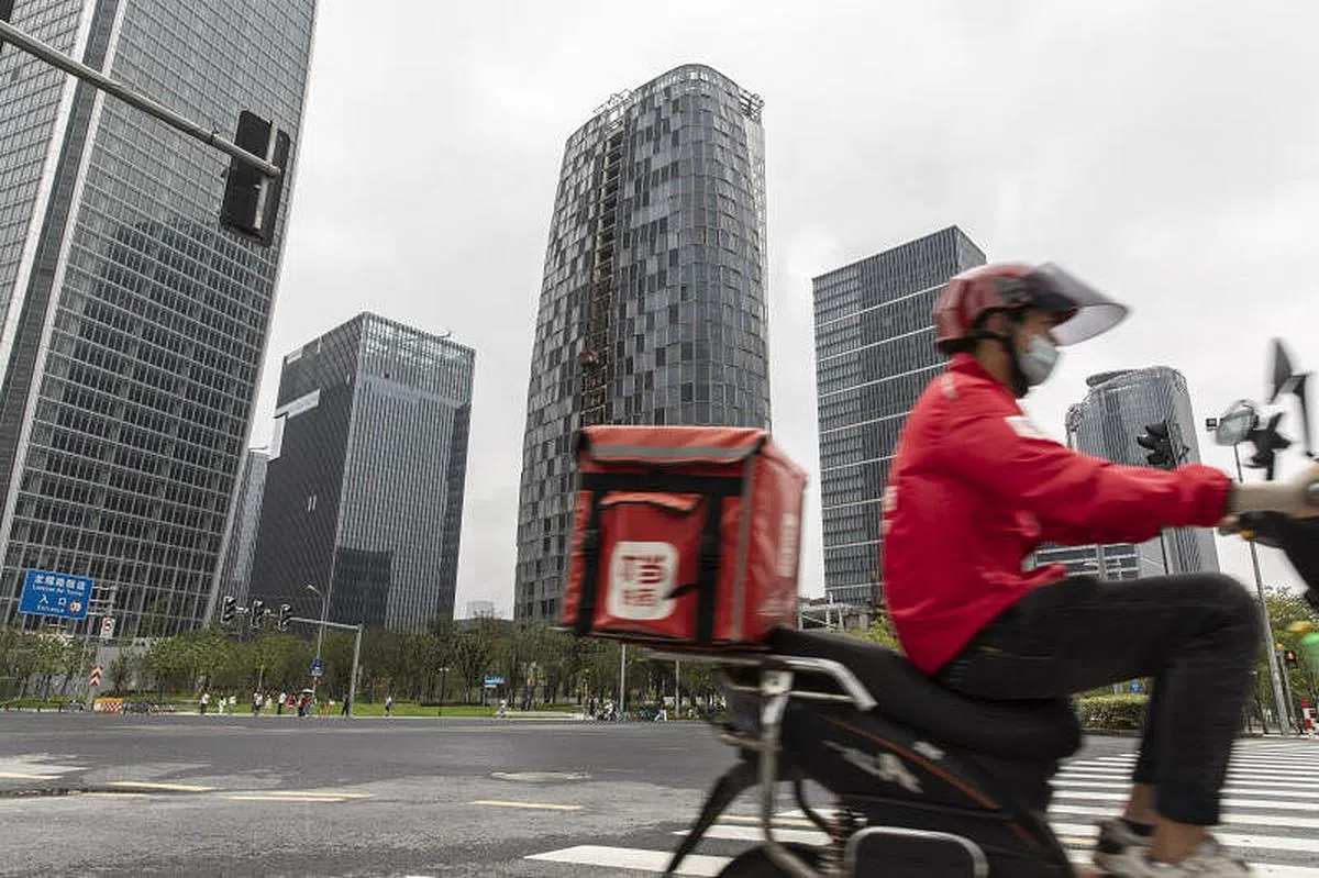 会议强调，推动更多低收入人群迈入中等收入行列。图为一名外卖员穿行在上海街头。（彭博社）