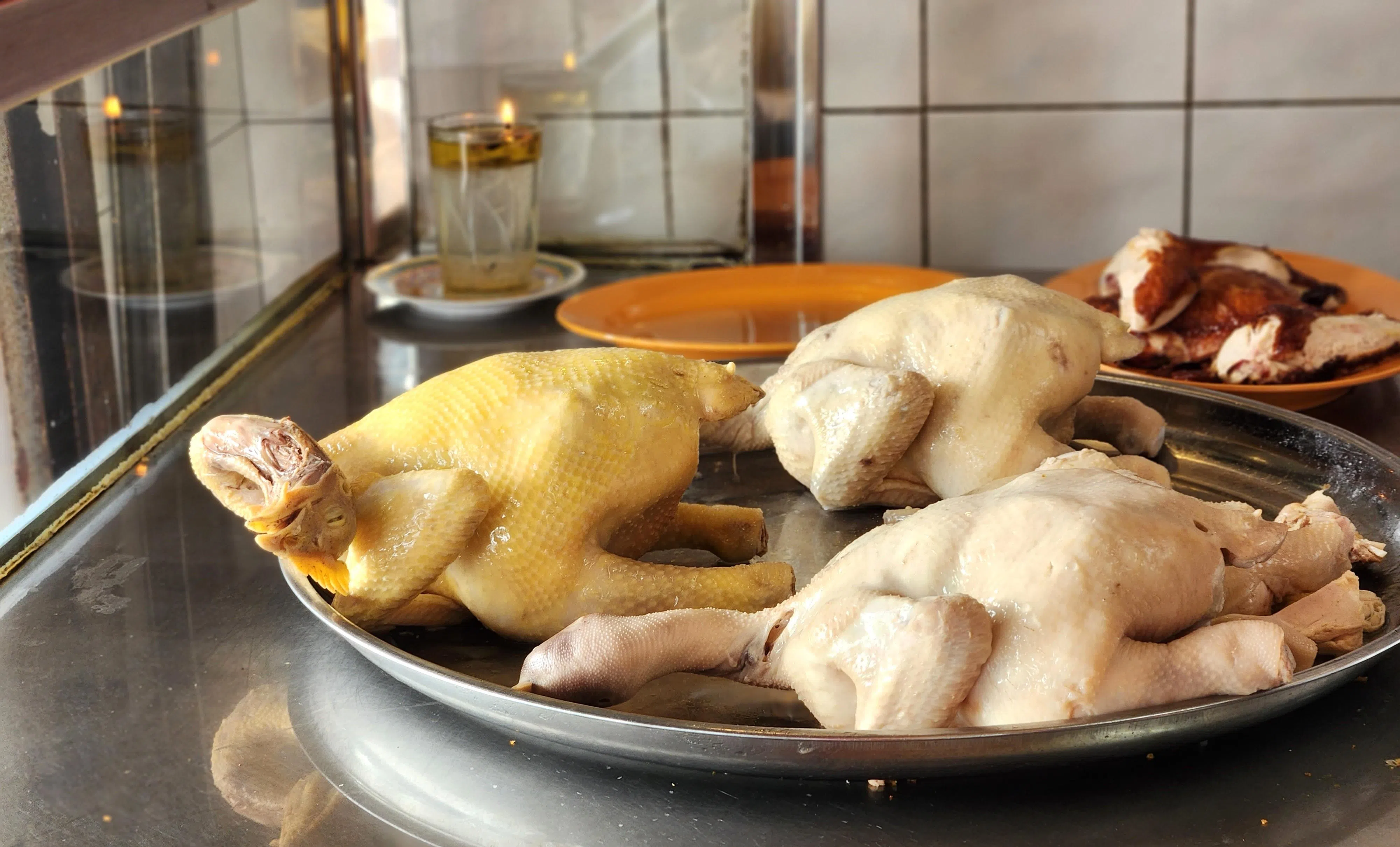 柔佛士乃瑞记海南鸡饭有提供菜园鸡（左）和肉鸡两种，摆在大盘内待斩切。（陈爱薇摄）