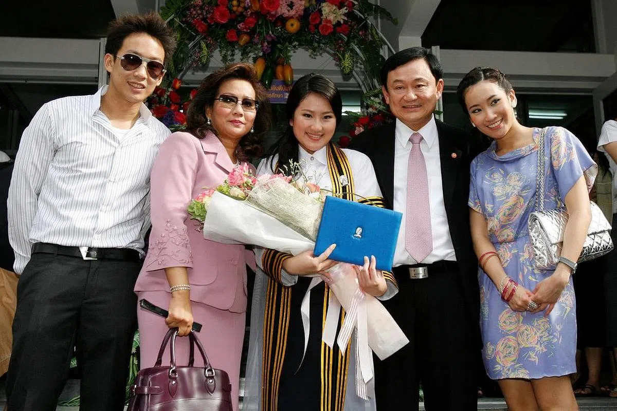 2008年7月，泰国前首相达信（右二）流亡海外前，在曼谷出席幼女佩通坦（中）的大学毕业典礼。（路透社）