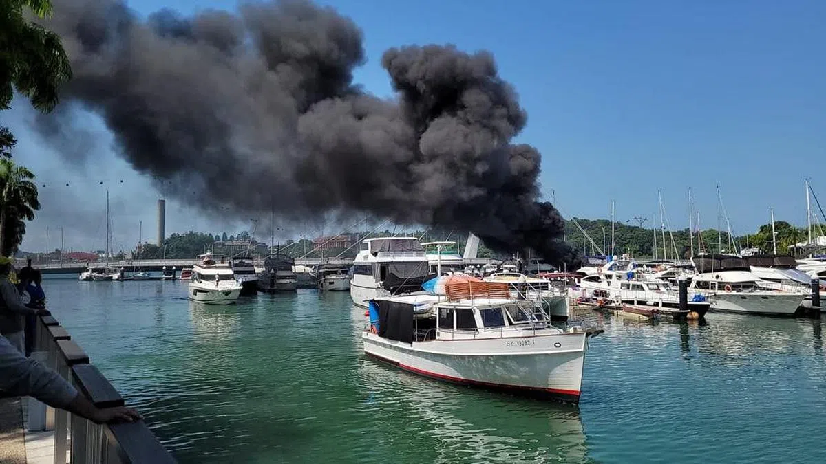 停靠吉宝湾滨海俱乐部的一艘游艇起火，现场冒起浓烟。（读者冯志伟提供）