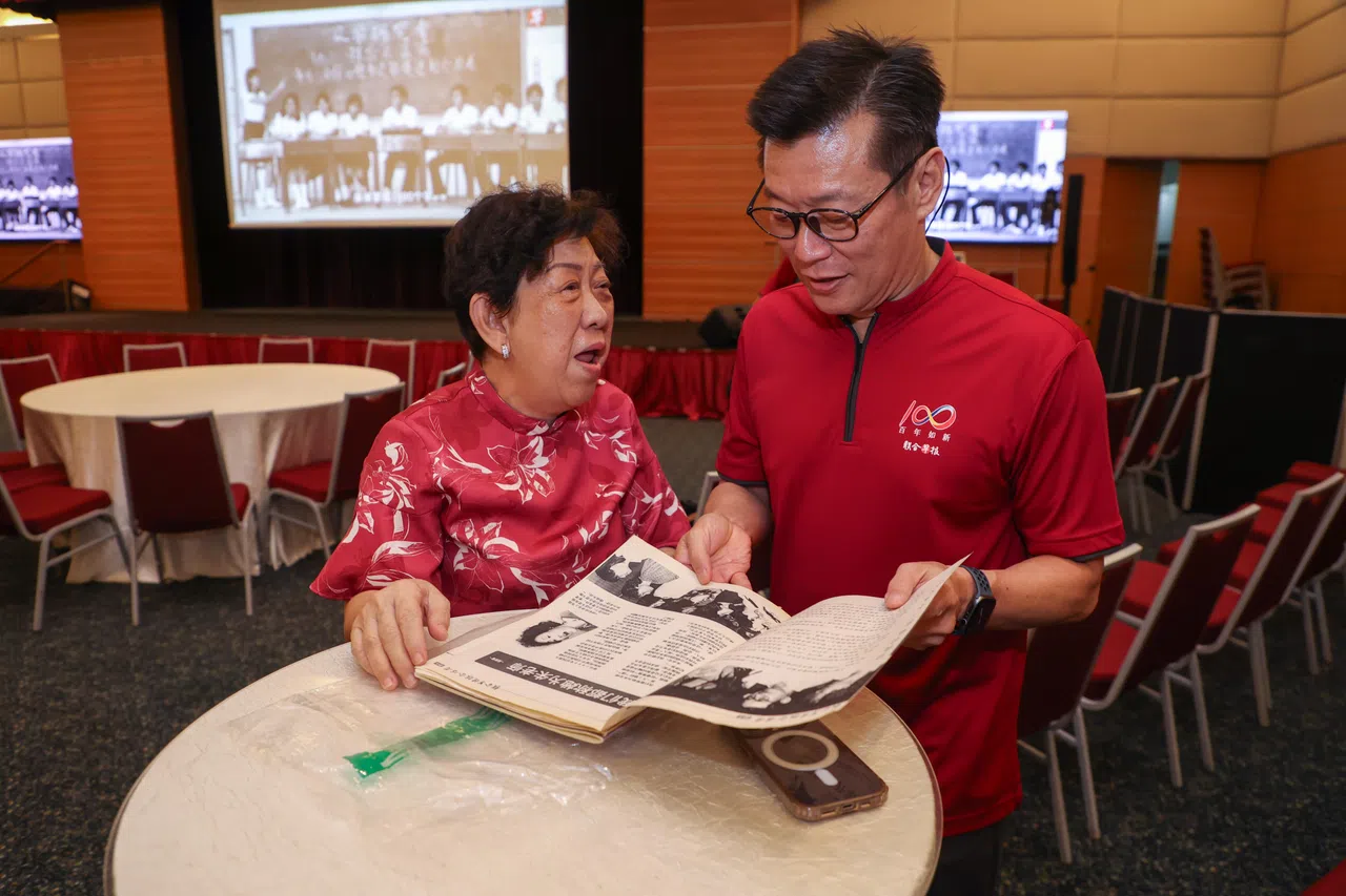 陈丽华（左）退休前服务于会计部，也是华文报合唱团的成员，她特地将珍藏已久的合唱团团讯捐赠给《联合早报》。图为早报总编辑吴新迪翻阅团讯，陈丽华同他分享合唱团以往的有趣点滴。（白艳琳摄）