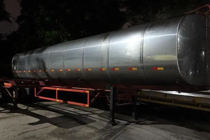 执法人员11月13日在巴西拉峇重型车辆停车场展开行动，对停泊的油罐车和附近的丛林进行检查。（新加坡关税局提供）