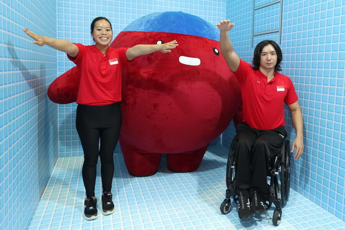 梅嫣婷（左）和杜维崧（右）联手残疾游泳世锦赛吉祥物“阿点”（中），与现场观众一起合影留念。（郑一鸣摄）